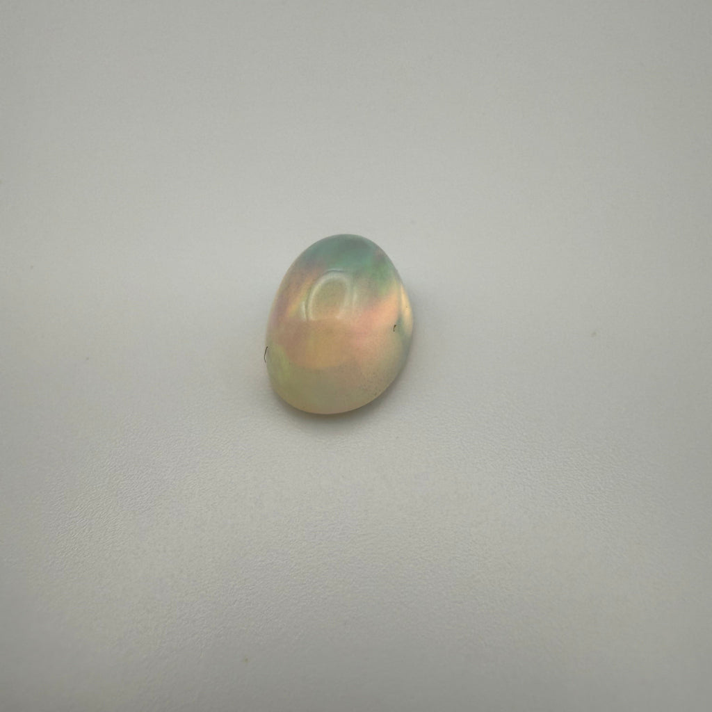 A birds eye view of a fiery 3 carat welo opal on a plain background