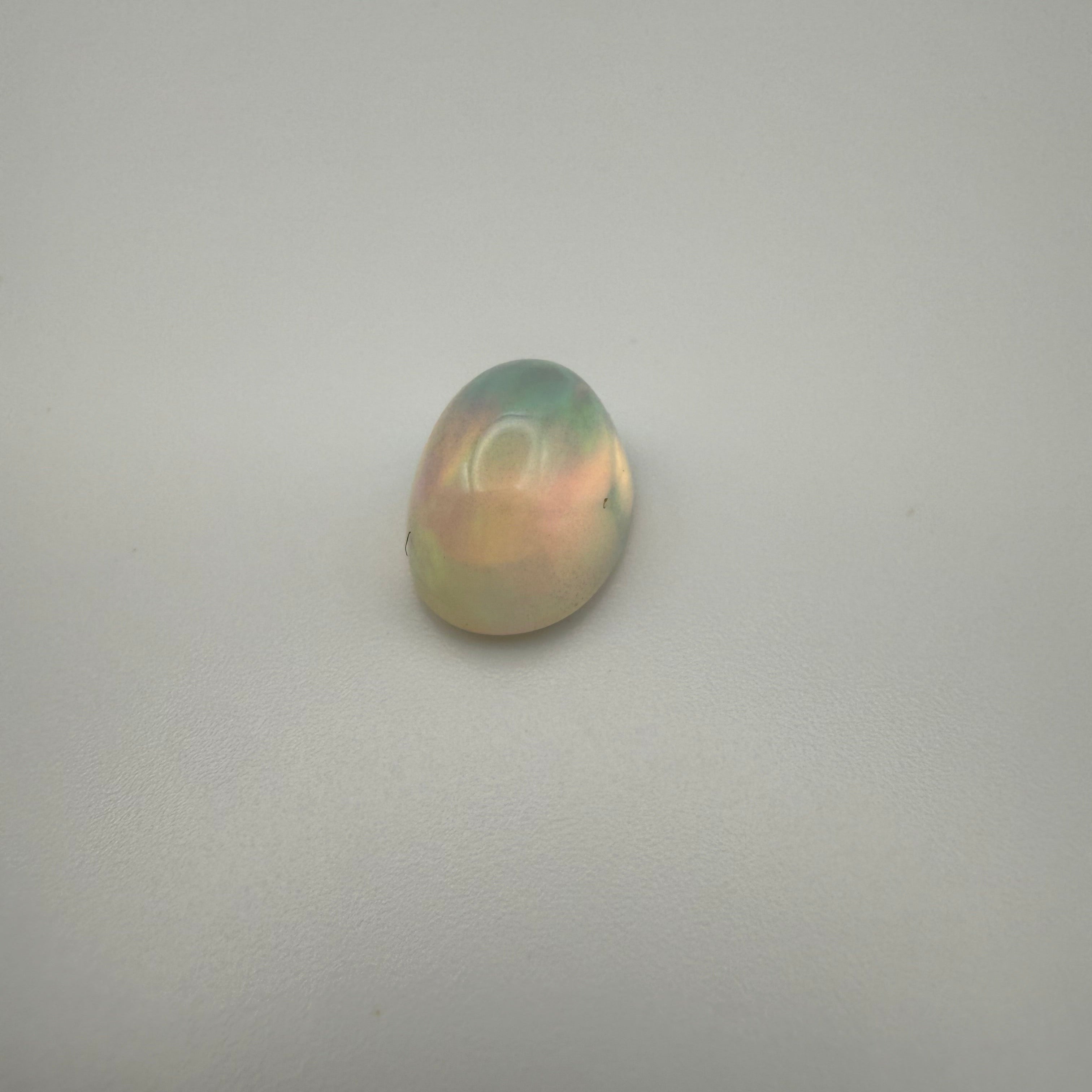 A birds eye view of a fiery 3 carat welo opal on a plain background