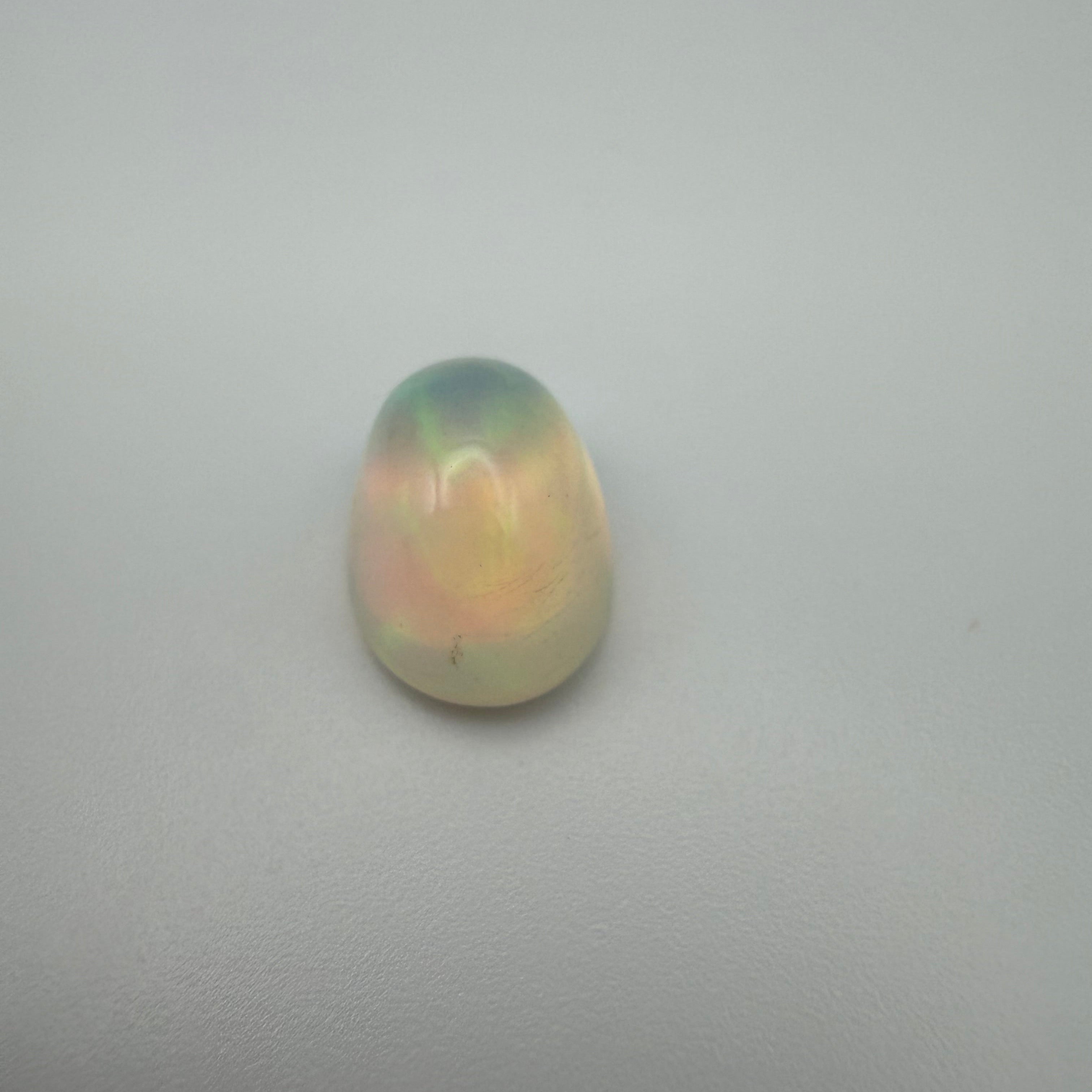 A birds eye view of a fiery 3 carat welo opal on a plain background