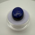 oval royal blue lapis lazuli cabochon on white display pad in clear gem holder