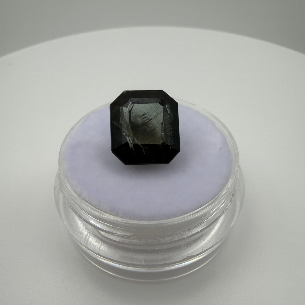 5.115 carat olive green rectangle cut tourmaline shown in a top-down on a container for size
