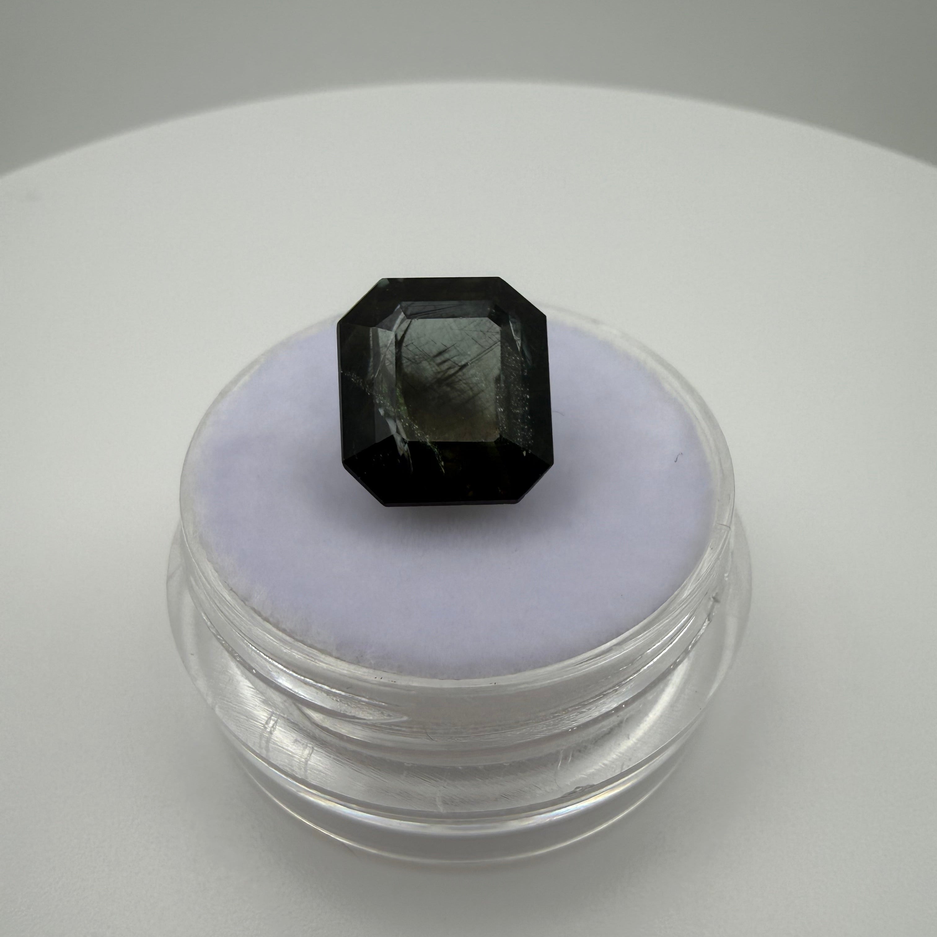 5.115 carat olive green rectangle cut tourmaline shown in a top-down on a container for size