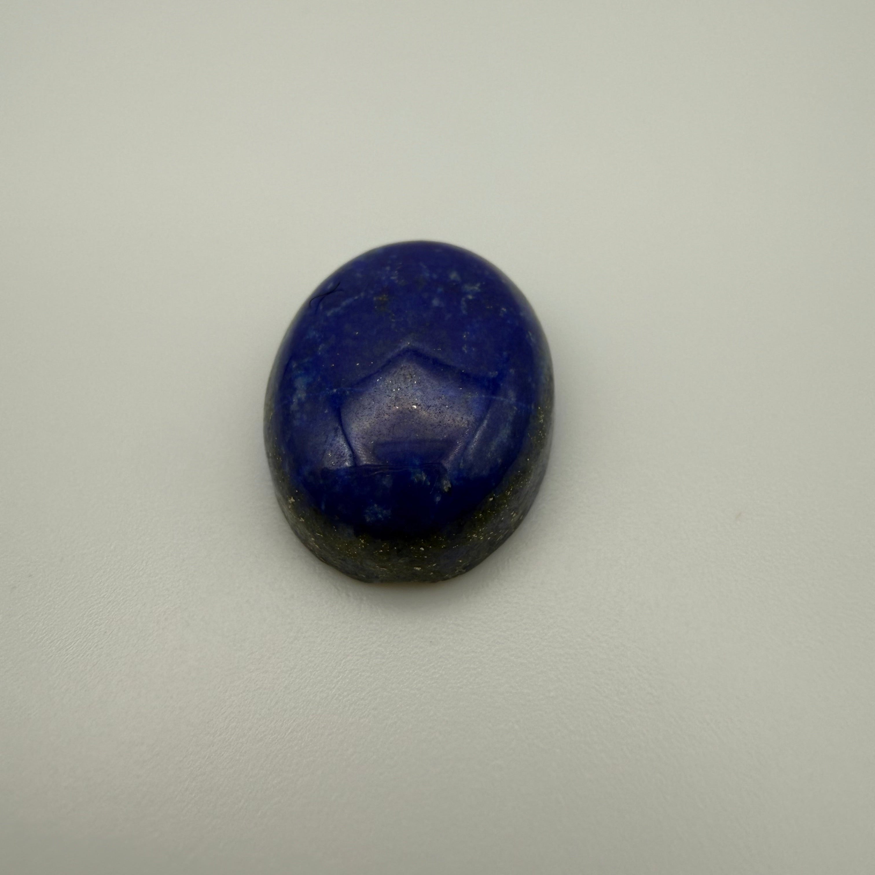 oval blue lapis lazuli cabochon gemstone on a light surface