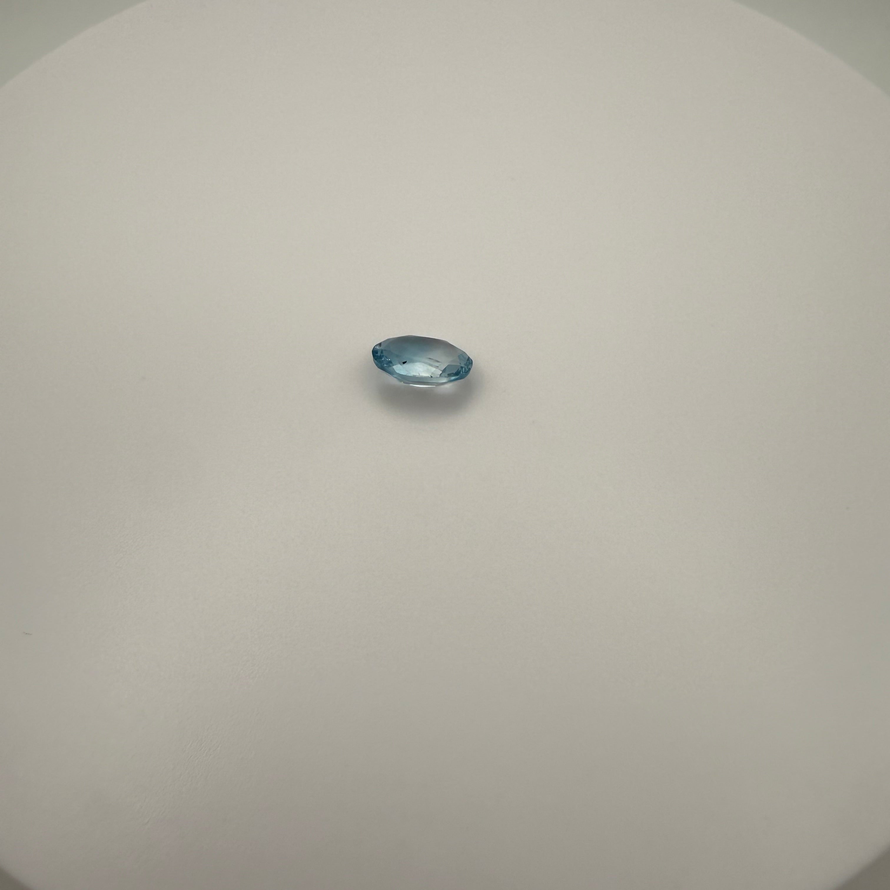 Oval faceted 2.05ct Swiss Blue Topaz gemstone on a smooth circular surface