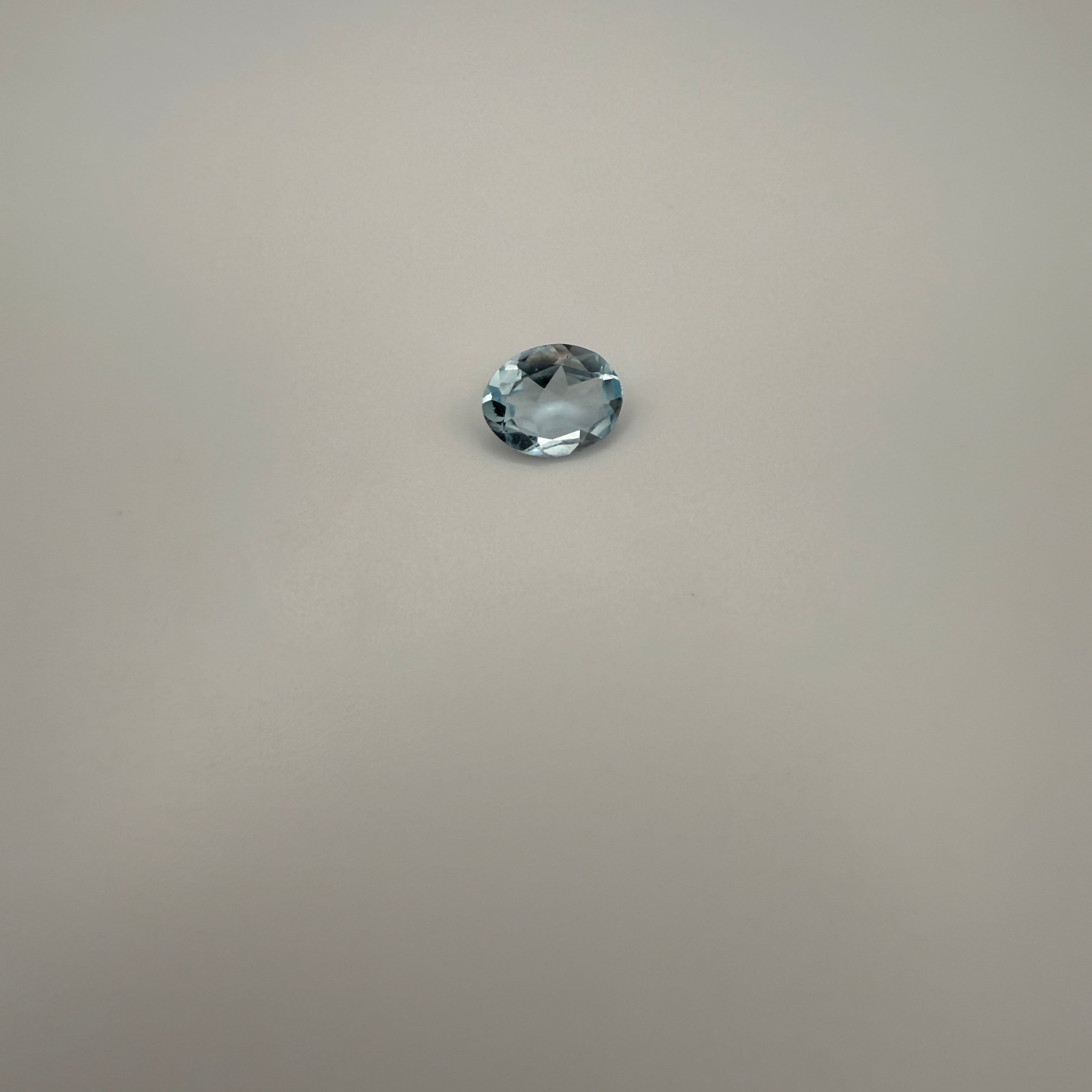 oval faceted 1.95ct Swiss Blue Topaz gemstone on a smooth neutral background