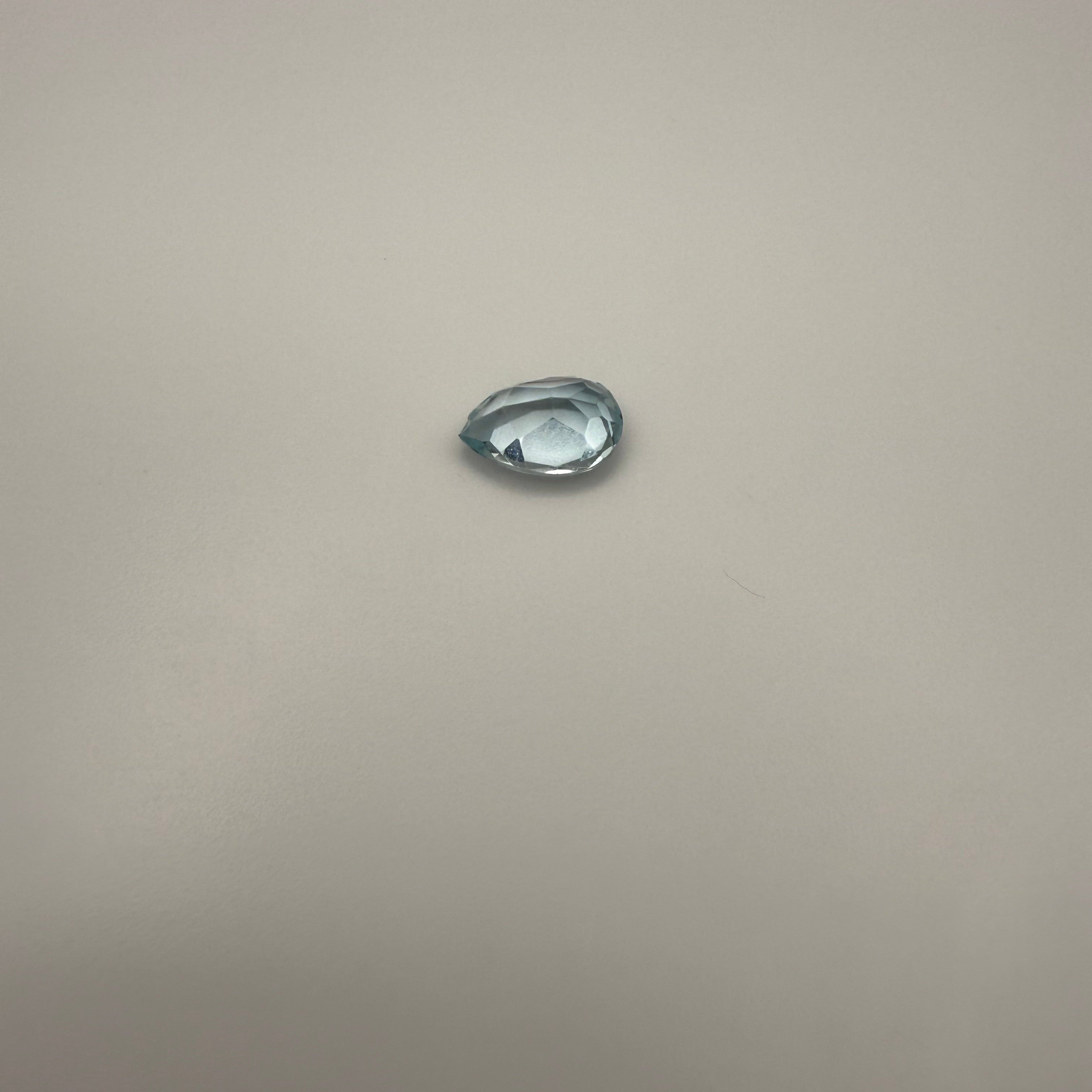 2.25ct Swiss Blue Topaz pear faceted gemstone resting on a light gray surface