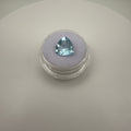 triangular faceted 3.6ct Swiss Blue Topaz gemstone on a purple cushion in a clear gem holder