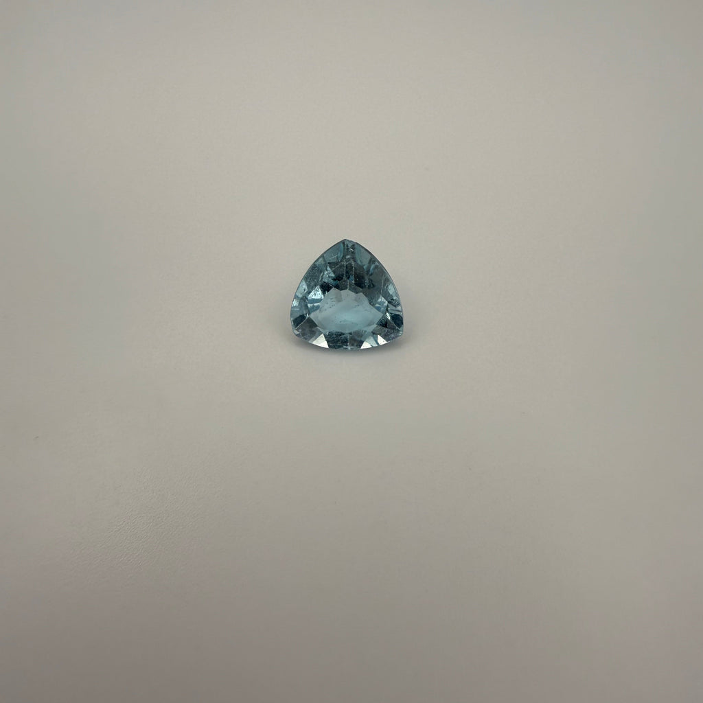 Triangular faceted 3.6ct Swiss Blue Topaz gemstone on a neutral background