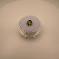 Round faceted 1.3ct yellow-green peridot gemstone on soft lavender holder