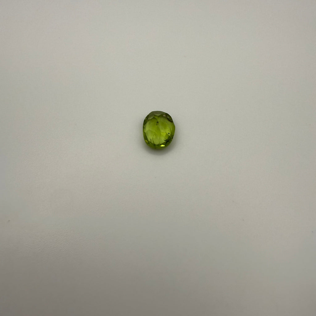 oval faceted 1.25ct yellow-green peridot gemstone on a plain background