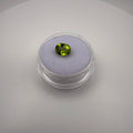 1.25ct oval faceted yellow-green peridot gemstone resting on a light-colored cushion in a round transparent gem holder.