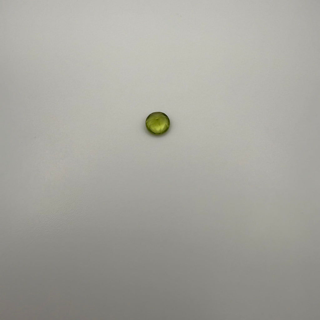 Round faceted 0.45ct yellow-green peridot gemstone on a light background