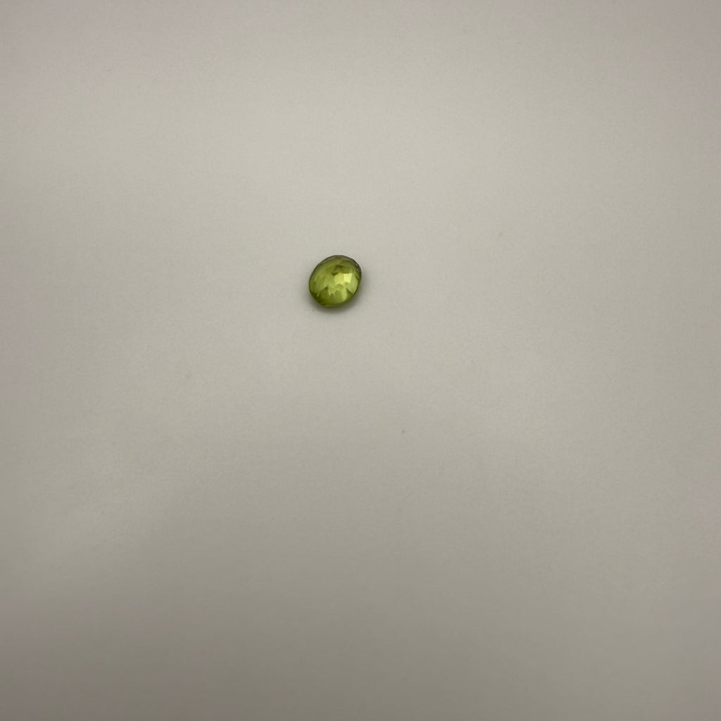 oval faceted 0.45ct yellow-green peridot gemstone on a light background