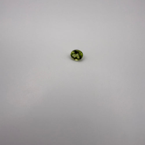 oval faceted yellow-green peridot gemstone on a light surface