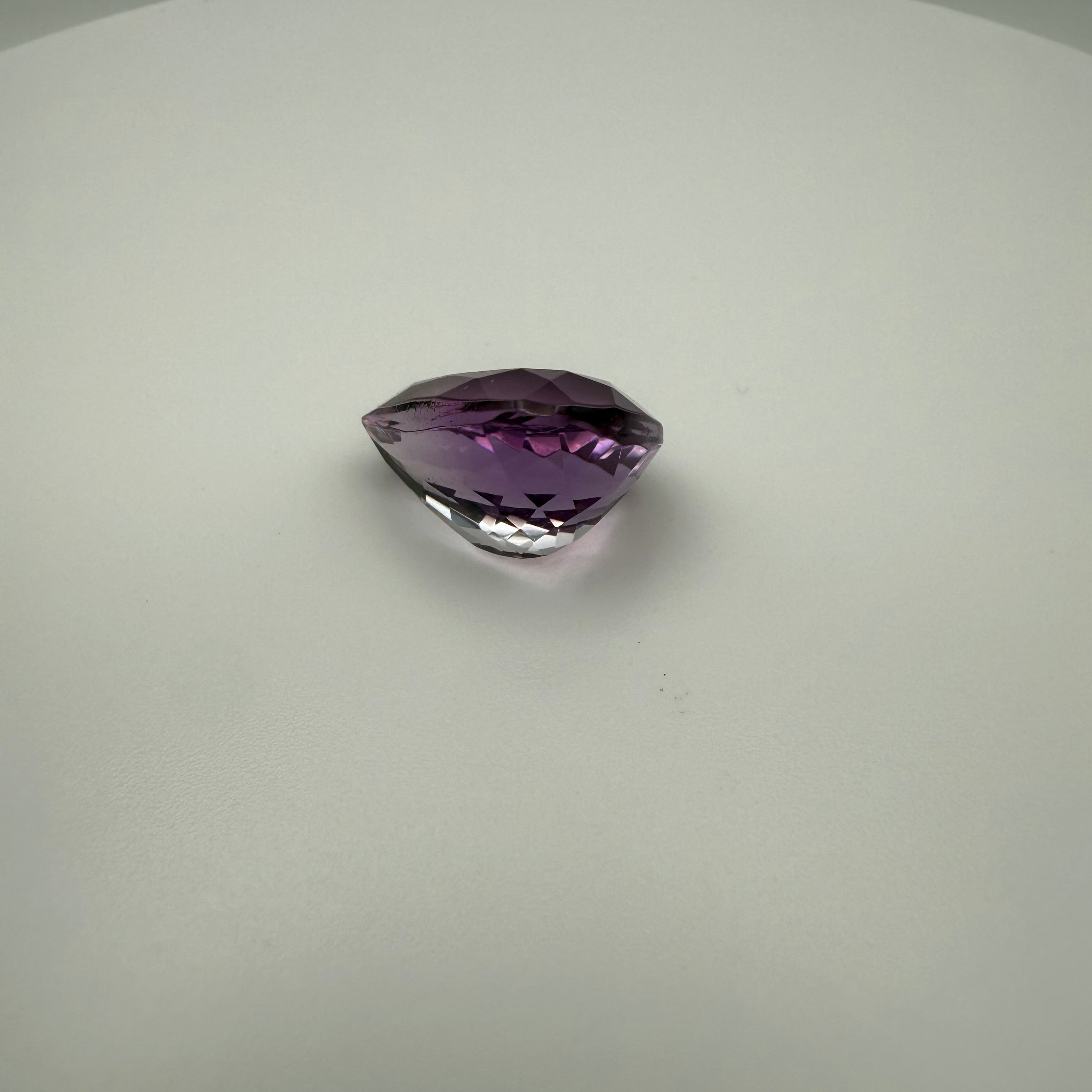 8.5ct pear faceted Rose de France Amethyst gemstone on a white surface