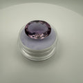 Macro top-down view of a 9.8ct lilac amethyst oval faceted gemstone sitting on a soft purple display holder.
