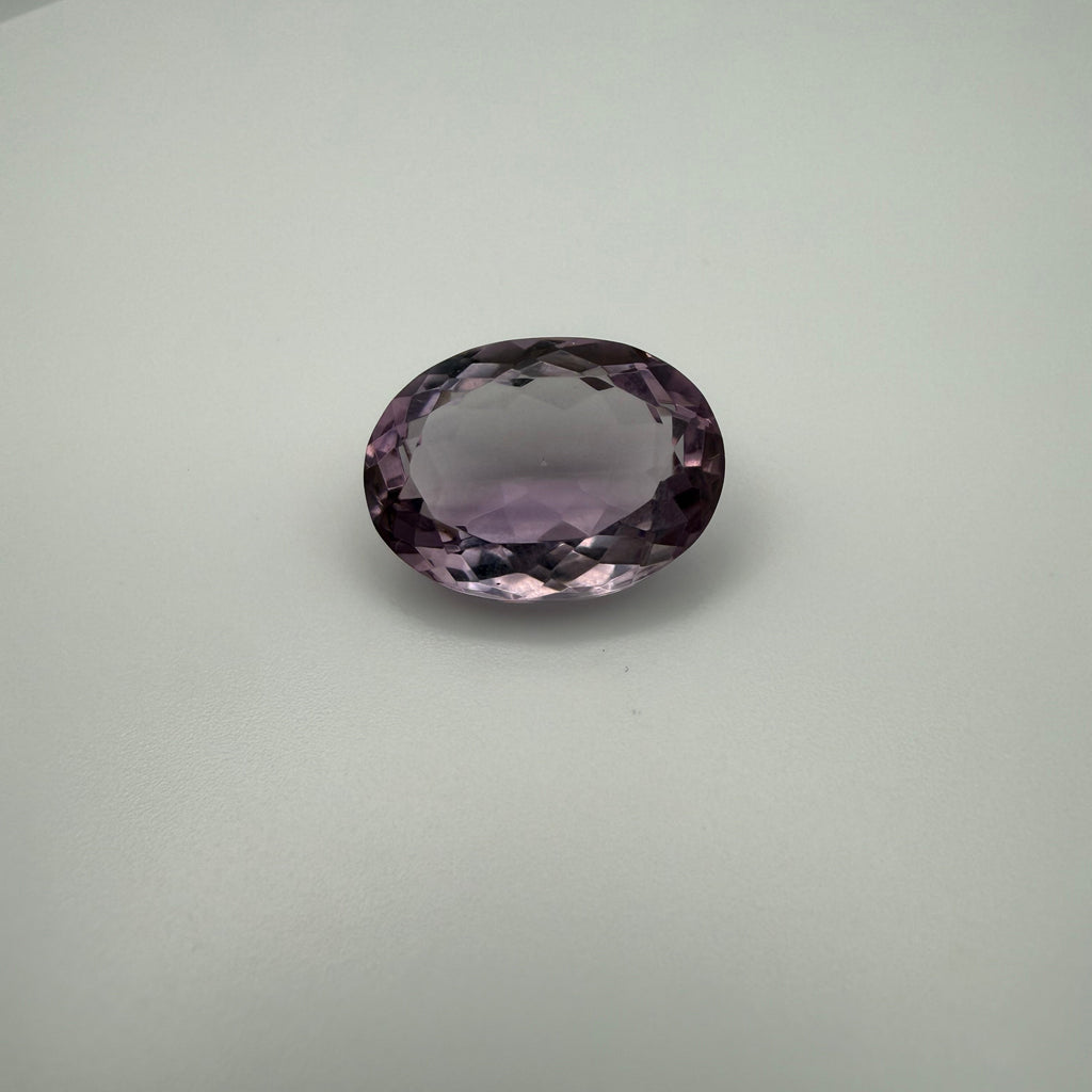 oval faceted lilac amethyst gemstone on a light background