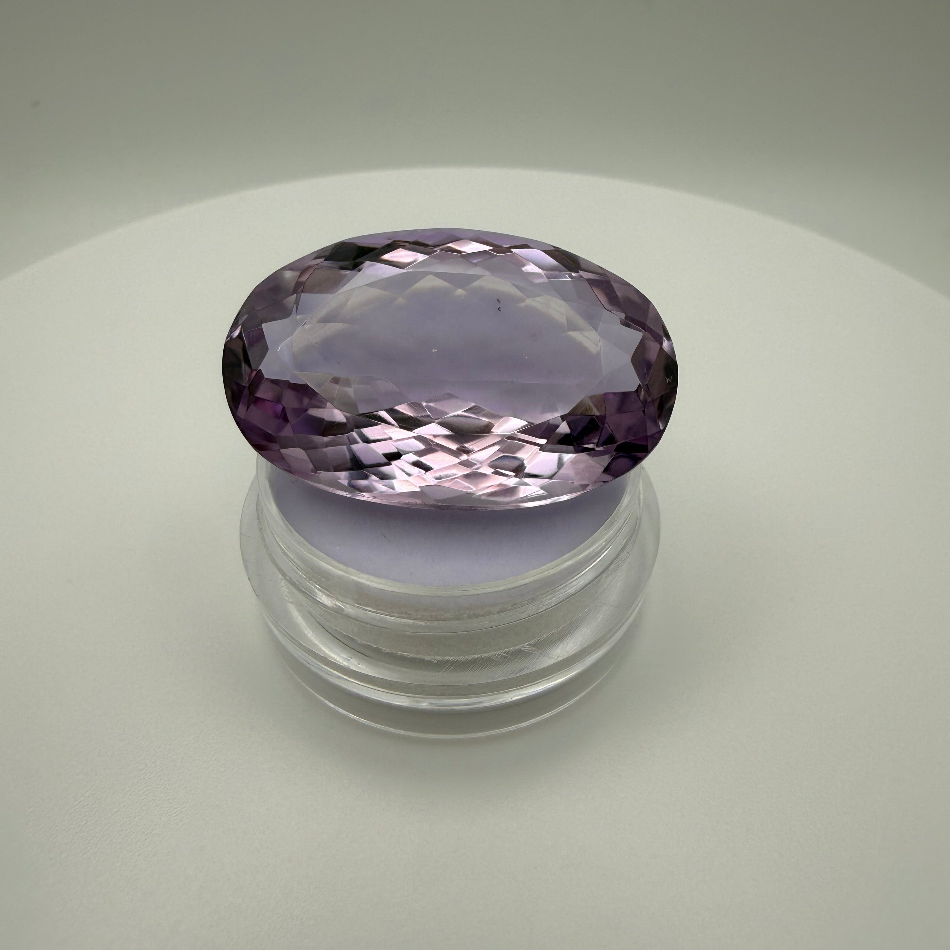 oval faceted 61.6ct Rose de France Amethyst displayed on a clear gem holder