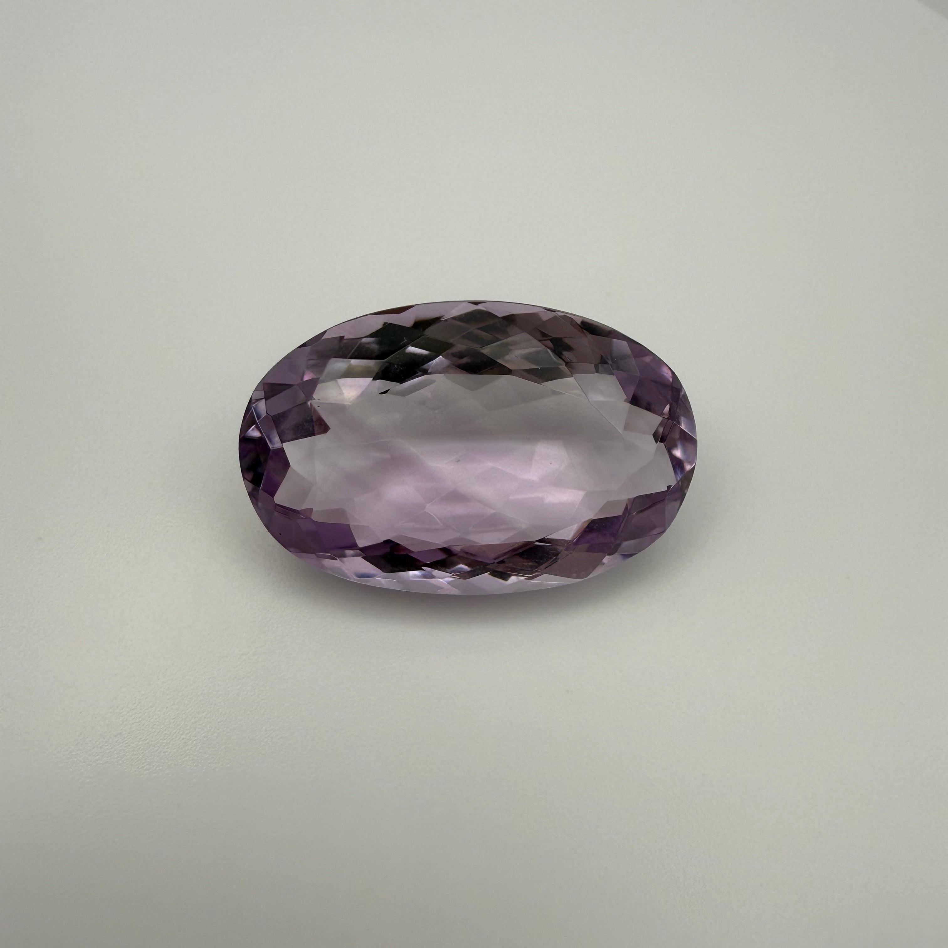 oval faceted 61.6ct Rose de France amethyst on light background