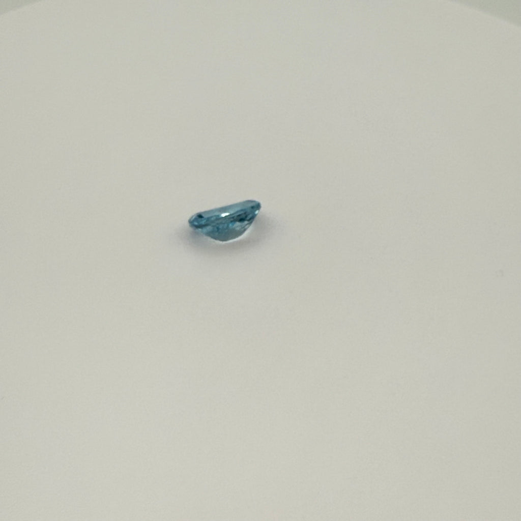 Close-up view of 2.0ct Swiss Blue Topaz oval faceted gemstone on a white background