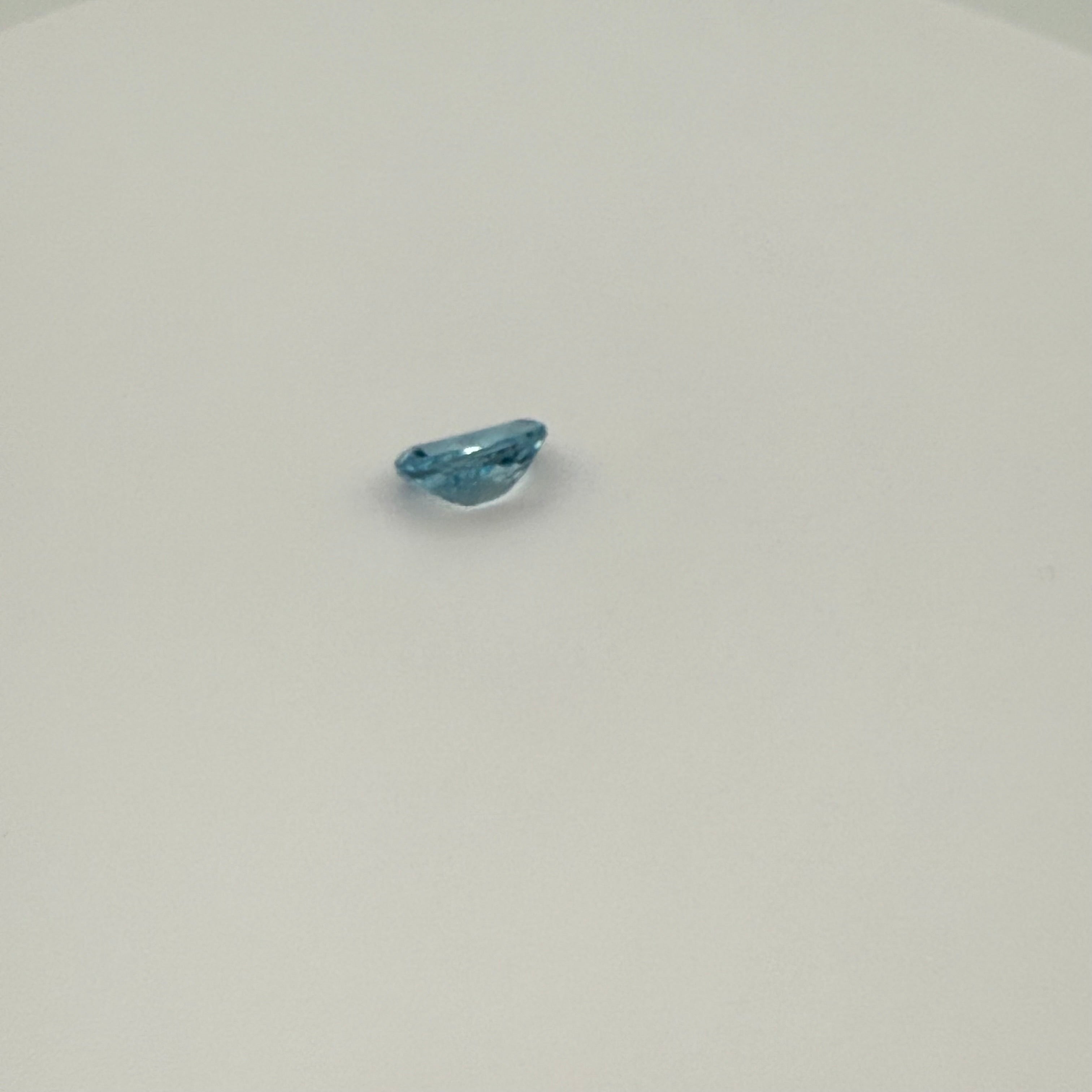 Close-up view of 2.0ct Swiss Blue Topaz oval faceted gemstone on a white background