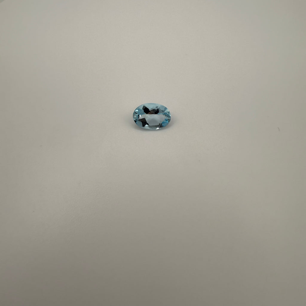 oval faceted 1.98ct Swiss Blue Topaz gemstone on a smooth white surface
