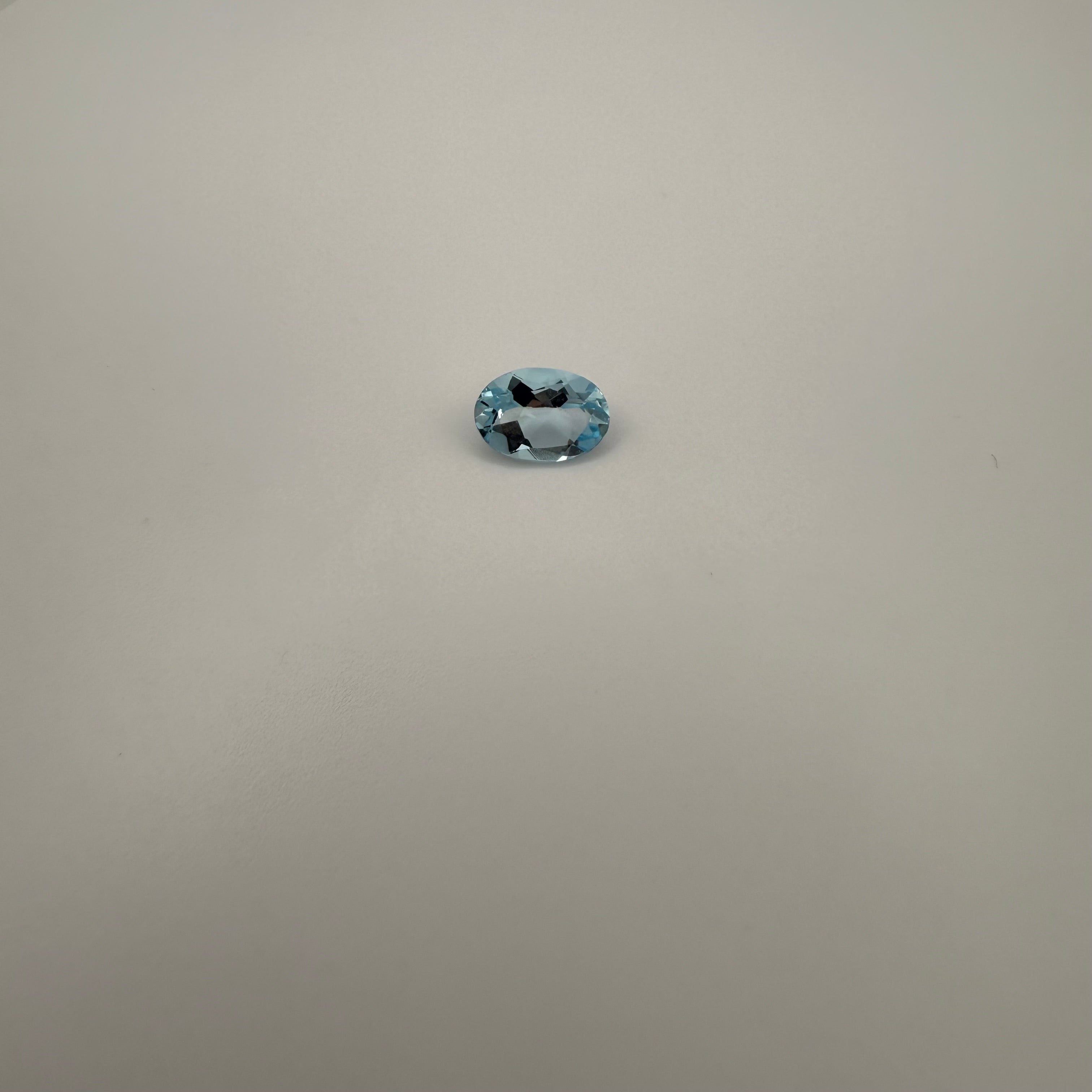 oval faceted 1.98ct Swiss Blue Topaz gemstone on a smooth white surface