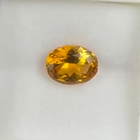 macro top down view of 0.9ct canary yellow tourmaline oval heated faceted gemstone on white background.